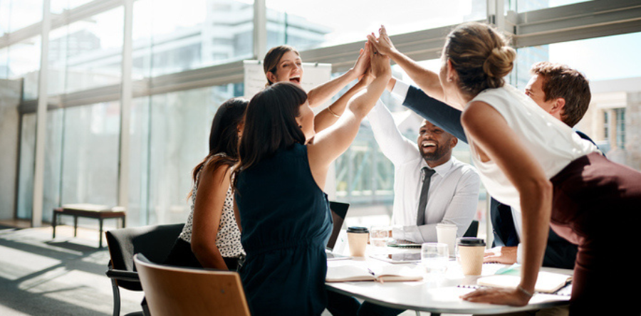 Shot of a group of businesspeople high fiving while sitting in a meeting